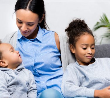 African American mother sitting on sofa with daughter